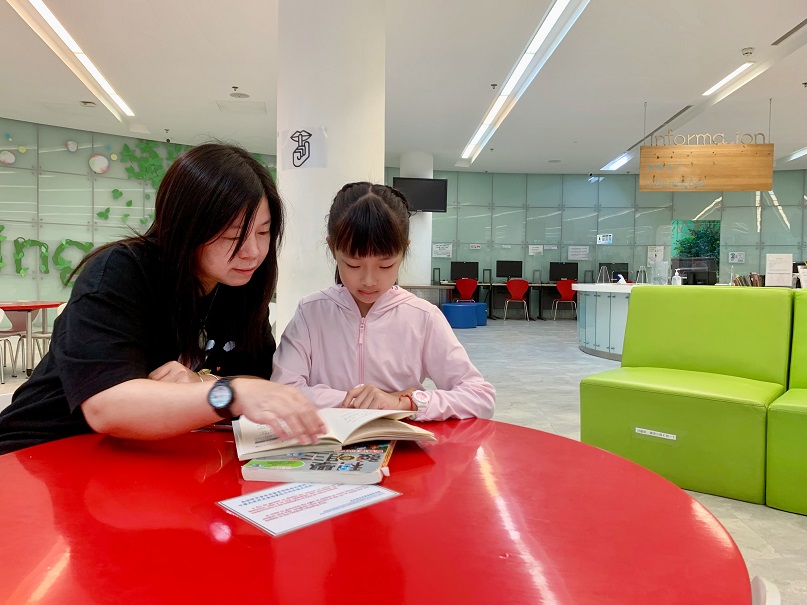 Charlie Yang and her daughter redeem prizes with reading points.